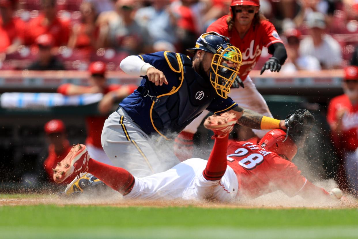 The Reds' Tommy Pham slides home safely as he scores on a two-out, bases-loaded double as the ball  gets past Brewers catcher Victor Caratini during the second inning Wednesday.