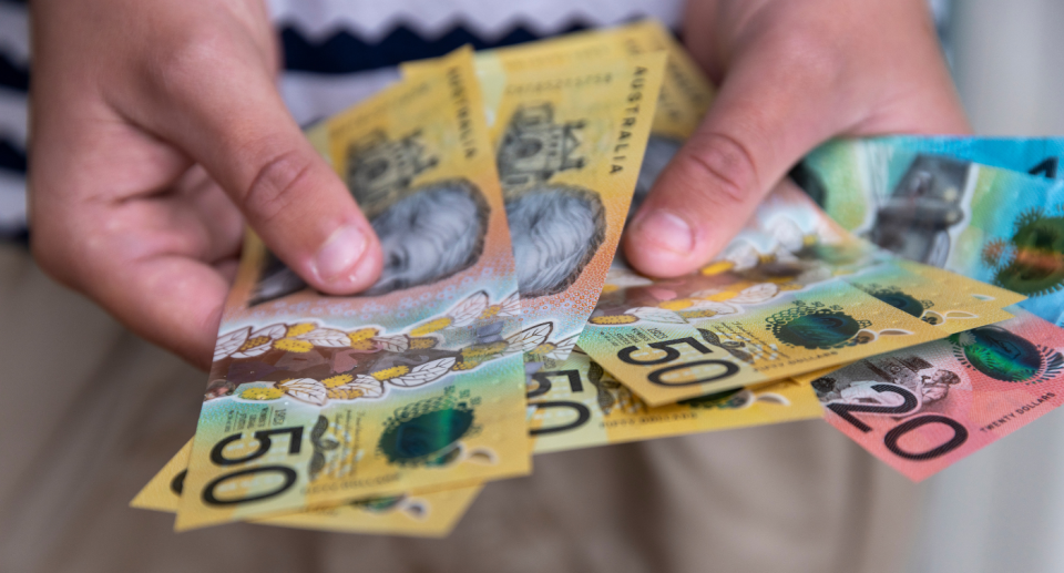 Hands holding Australian cash money.