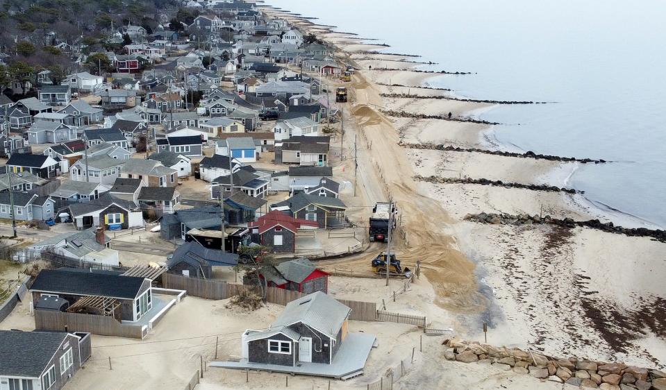 Truck loads of sand are dumped and spread on Nantucket Sound-facing beaches on Wednesday in Dennisport, off Old Wharf Road.