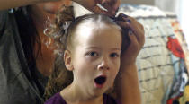 In this May 6, 2019, photo, Amie Schofield, rear, does her daughter Victory hair at their home in Ogden, Utah. Victory has XXY chromosomes. Amie and her husband decided to raise Victory without pushing either gender. There would be no surgery. At 18 months, Victory began gravitating toward dresses and bows, and loudly insisting on wearing her hair long. (AP Photo/Rick Bowmer)