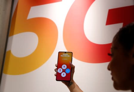 An employee displays a Huawei 5G Smartphone Mate 20X smartphone at a Sunrise telecommunications shop in Opfikon