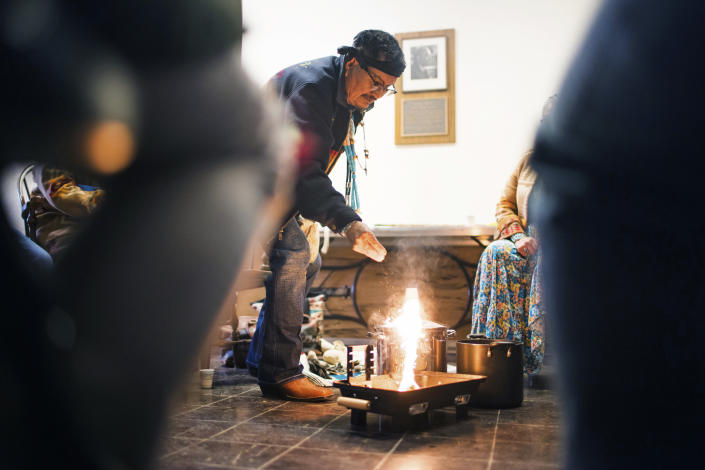 In this photo provided by Dartmouth College, Medicine Man Herbert Wilson, a citizen of the Diné, or Navajo Nation, from Thoreau, N.M, lights the ceremonial fire for the cleansing ceremony he was leading in Carpenter Hall at Dartmouth College, April 28, 2023, in Hanover, N.H. The college announced in March 2023 that it housed partial Native American skeletal remains in their collection. Dartmouth has set in motion an effort to repatriate the remains to the appropriate tribes. (Katie Lenhart/Dartmouth College via AP)