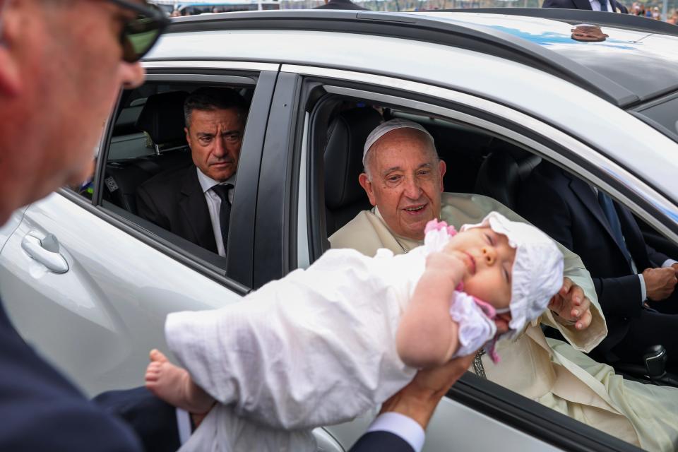 Pope Francis cheers at a child on his way to the Belem Cultural Center in Lisbon in August, where he attended International World Youth Day.