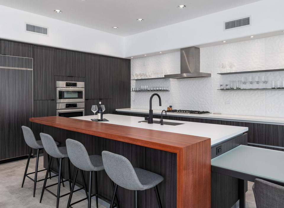 A modern kitchen island with a quartz counter height surface and a wood bar height surface.