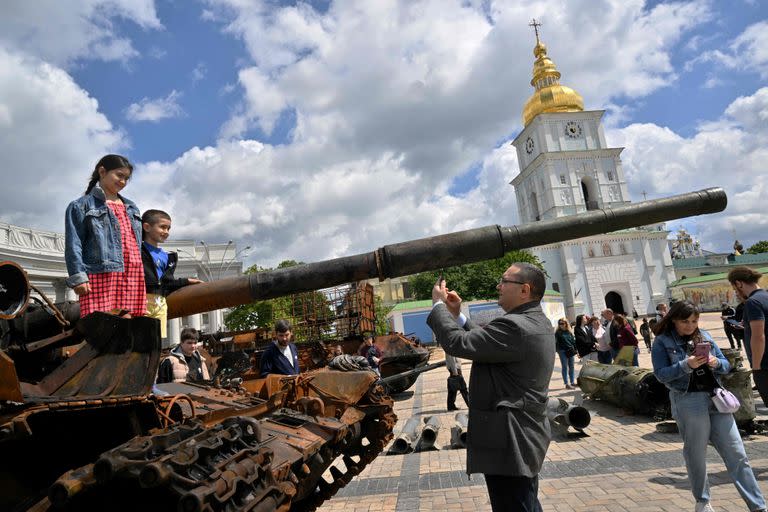 Chicos posan para la foto sobre un tanque ruso destruido en una muestra sobre la guerra en el centro de Kiev