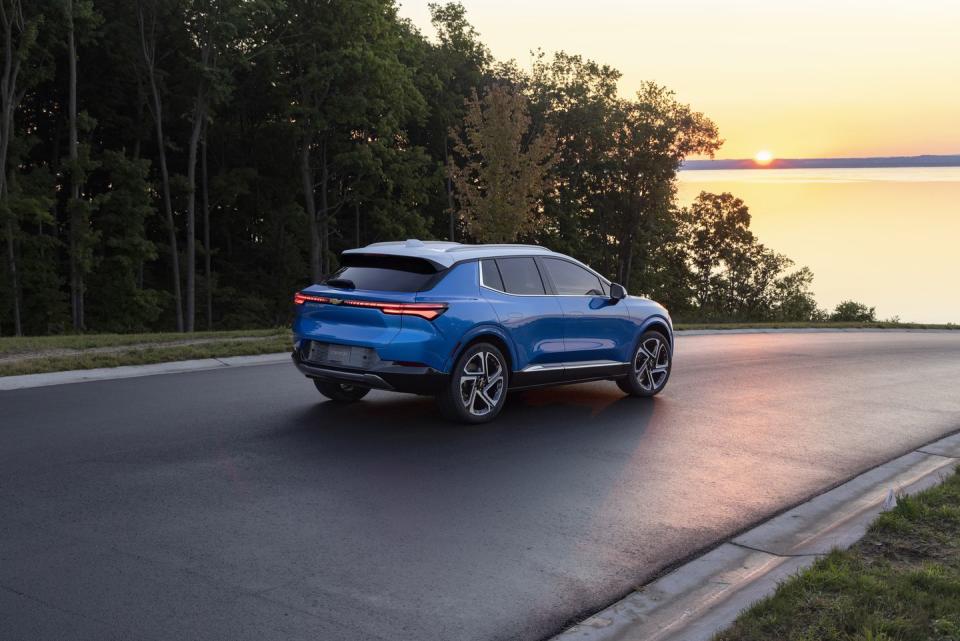 rear 34 view of 2024 chevrolet equinox ev 3lt in riptide blue driving towards sunset preproduction model shown actual production model may vary visit chevycomequinoxev for availability