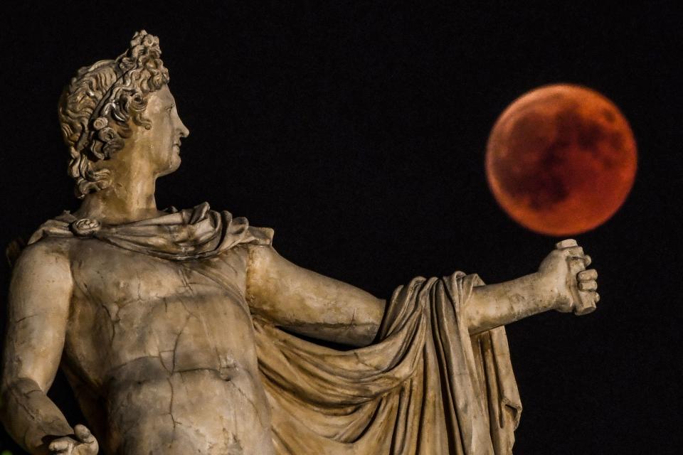 Rising beside a statue of the ancient Greek god Apollo in central Athens, Greece. (Photo: ARIS MESSINIS via Getty Images)