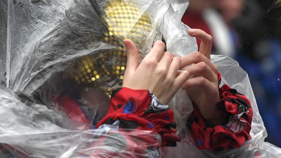 Eine Frau schützt sich mit einem Poncho vor dem Regen beim Rosenmontagszug in Köln (Archiv). Auch in diesem Jahr soll es in den Karnevalshochburgen nass werden.