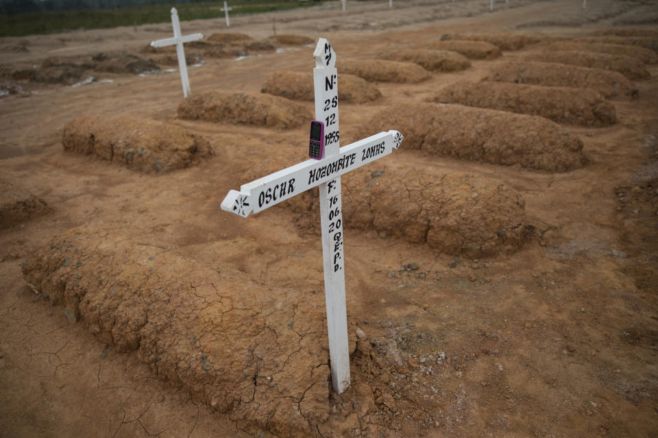 The cell phone of gravedigger Rider Sol Sol rests on a white cross marking the grave of a person who died from the new coronavirus, in a cemetery recently developed to bury victims of COVID-19, along a remote road known as “Kilometer 20,” on the outskirts of Pucallpa, in Peru’s Ucayali region, Wednesday, Sept. 2, 2020. The 48-year-old father of four said he and a crew of gravediggers buried up to 30 people a day at the height of the new coronavirus pandemic. (AP Photo/Rodrigo Abd)