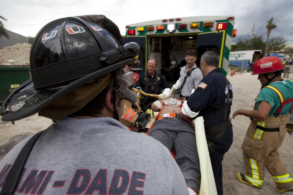 DORAL, FL - OCTOBER 10: In this handout from Miami-Dade Fire Rescue, Miami-Dade Fire Rescue workers place an injured person into an ambulance after pulling him from under the rubble of a four-story parking garage that was under construction and collapsed at the Miami Dade College's West Campus on October 10, 2012 in Doral, Florida. Early reports indicate that one person was killed, at least seven people injured and an unknown number of people may be buried in the rubble. (Photo by Miami-Dade Fire Rescue via Getty Images)