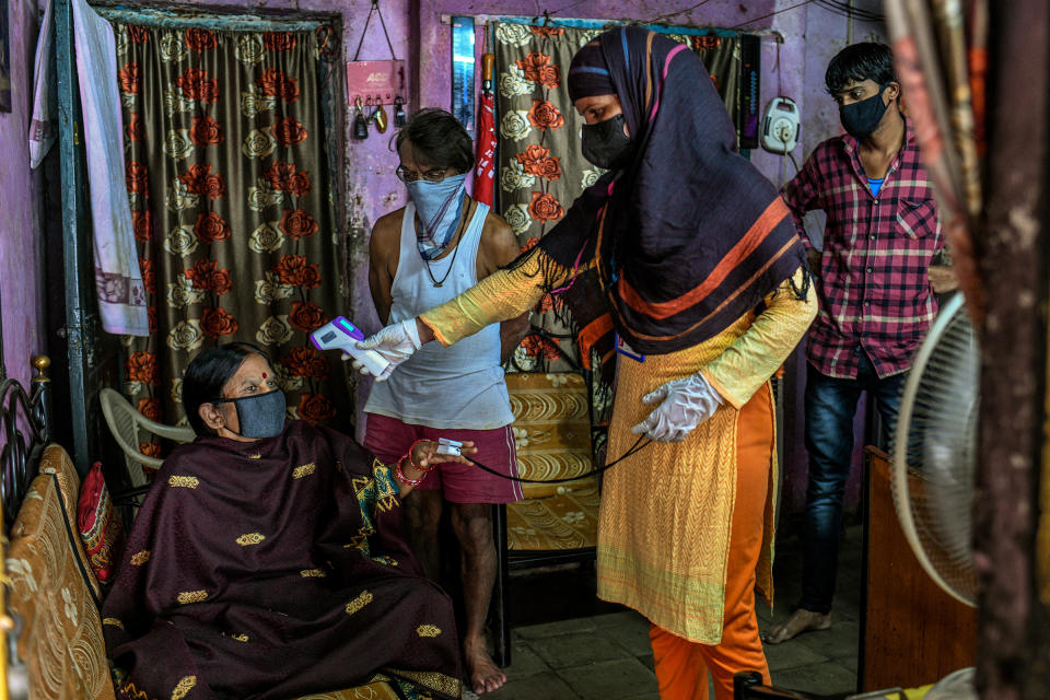 A health care worker checks a woman's temperature and oxygen saturation in the Dhole Patil slum on Aug. 10.<span class="copyright">Atul Loke for TIME</span>