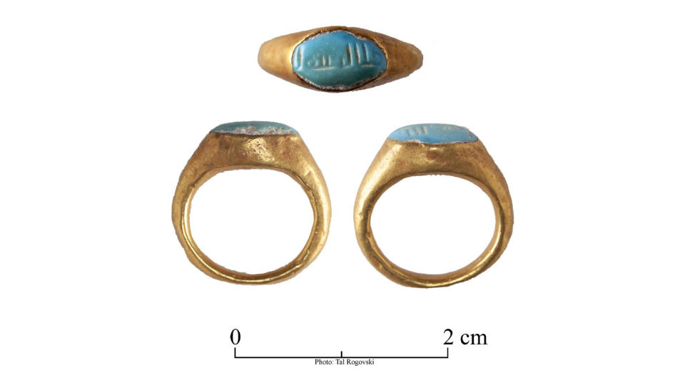 This gold ring contains a turquoise gem with the inscription 