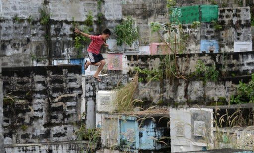 A boy jumps from one apartment type grave to another at a cemetery in Manila on October 31, 2012. Millions across the Philippines visited cemeteries Thursday to pay respects to their dead, in an annual tradition that combines Catholic religious rites with the country's penchant for festivity