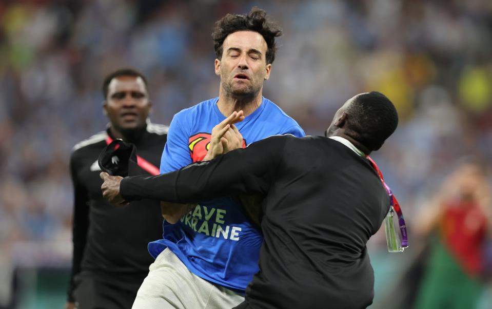 A pitch invader wearing a Superman t-shirt bearing the phrase Save Ukraine is shackled by security staff during the FIFA World Cup Qatar 2022 Group H match between Portugal and Uruguay at Lusail Stadium on November 28, 2022 in Lusail City, Qata - Youssef Loulidi/Fantasista/Getty Images