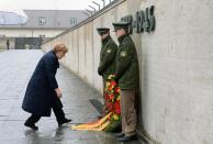 German Chancellor Angela Merkel bows to adjust the ribbons of a wreath during a ceremony to mark the liberation of prisoners at the former Nazi concentration camp in Dachau, southern Germany, on May 3, 2015