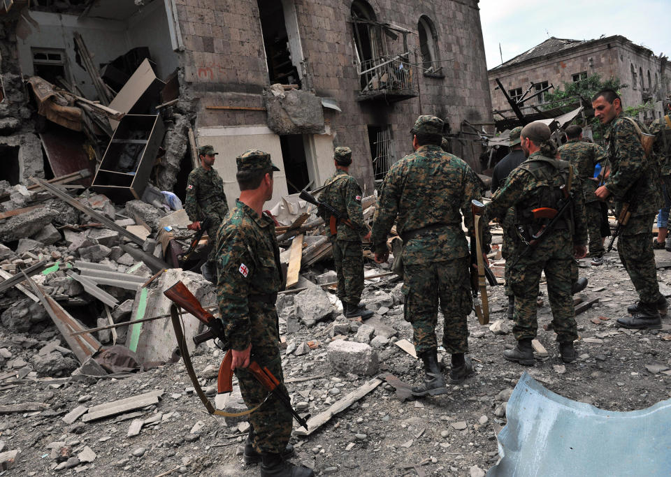 Georgian soldiers watch a building hit by bombardments in Gori on August 9, 2008. Georgian President Mikheil Saakashvili declared a "state of war" on August 9 as his troops battled it out with Russian forces over the breakaway province of South Ossetia. Russian warplanes bombed the Georgian city of Gori killing civilians.<span class="copyright">Dimitar Dolkoff—AFP/Getty Images</span>