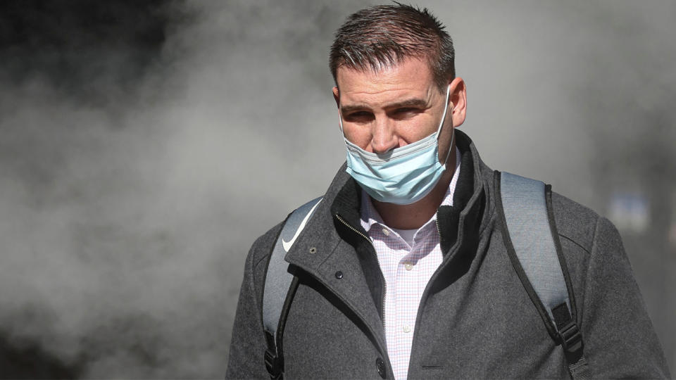 A man wearing a mask walks through a cloud of steam in Manhattan.