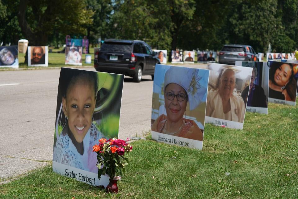 People drive past photos of Detroit residents and people with connections to Detroit who died during the pandemic sit on display as part of the Memorial Drive on Belle Isle in Detroit on Monday, Aug. 31, 2020.