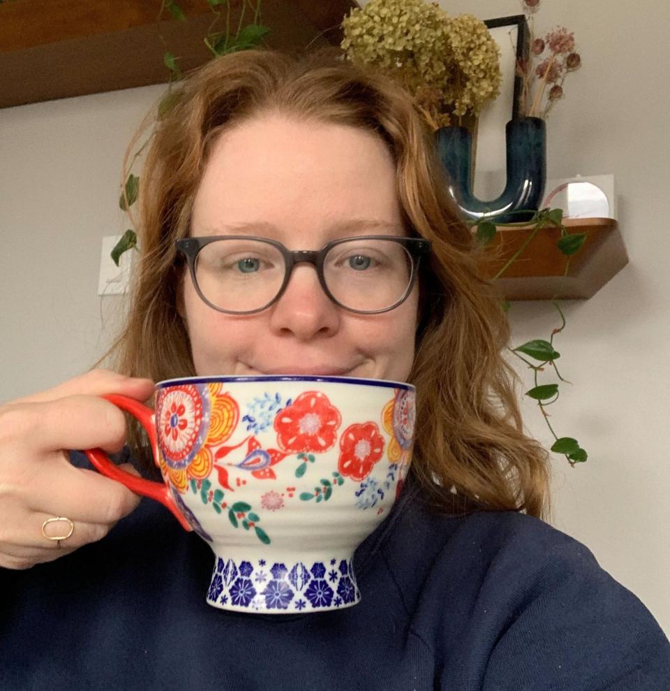 A woman smiling with a large cup of her beloved java.