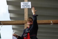 A woman stands by a cross with a note reading in Italian "Draghi like Pontius Pilates" as Alitalia workers stage a protest at the Rome Leonardo Da Vinci international airport in Fiumicino, Friday, Sept. 24, 2021. Alitalia, which has been in the red for more than a decade, is due to formally exit the airline market next month and be replaced by a new national carrier ITA, or Italy Air Transport. The European Commission has given the go-ahead to a 1.35 billion euro ($1.58 billion) injection of government funding into the new airline, but ITA is only planning to hire around a quarter of the estimated 10,000 Alitalia employees.(Cecilia Fabiano/LaPresse via AP)