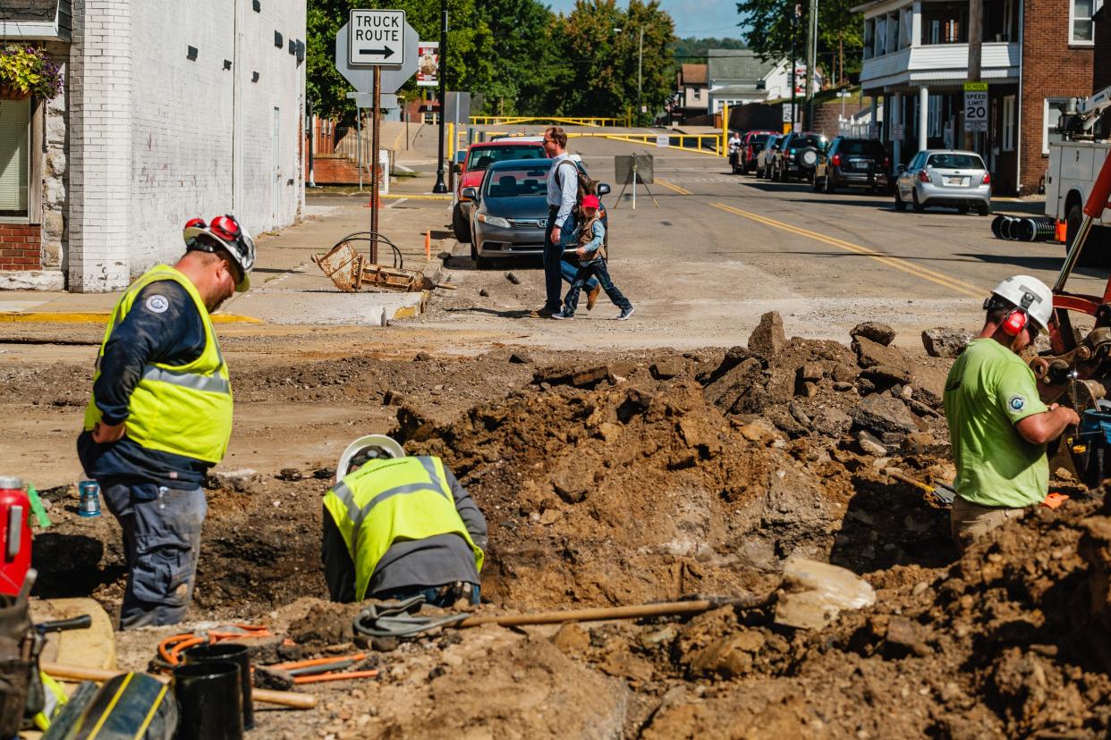 A father and son cross the road at the intersection of Grant and North Third streets in Dennison, as workers make repairs to a ruptured gas line.