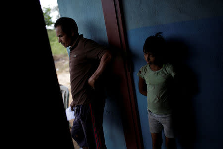 Tulio Medina (L), father of Eliannys Vivas, who died from diphtheria, stands next to one of his daughters at the entrance of their home in Pariaguan, Venezuela January 26, 2017. REUTERS/Marco Bello