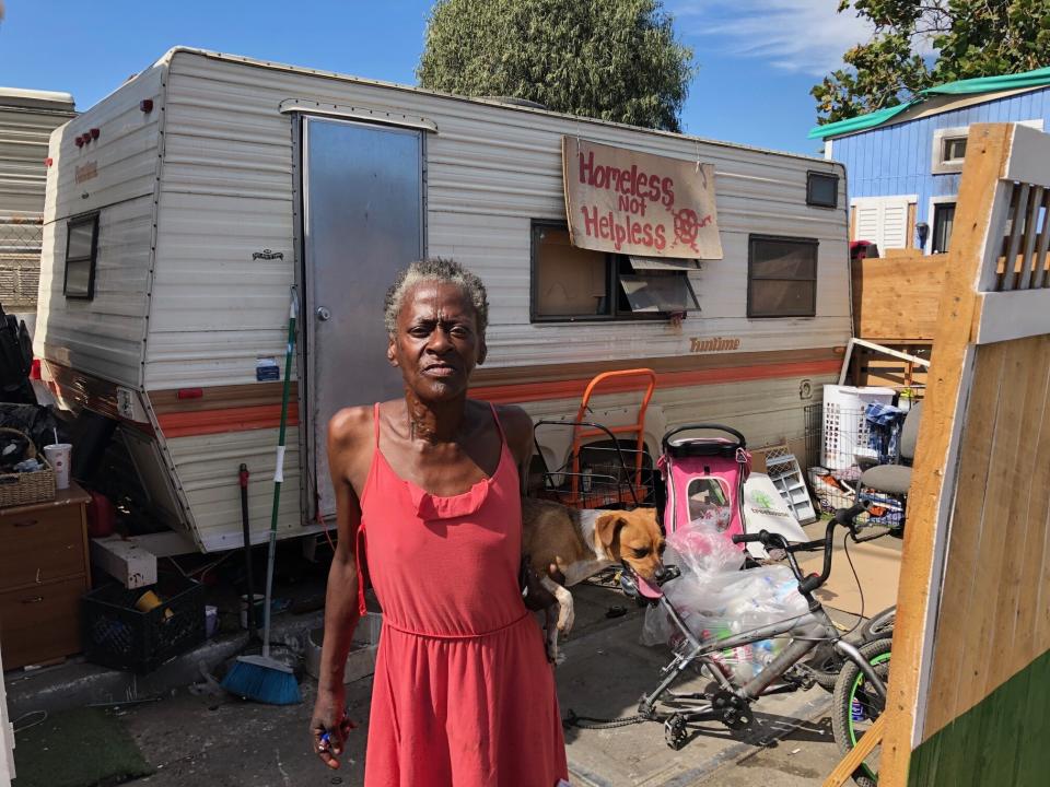 Claudette Smith stands in front of her mobile home in an Oakland homeless encampment, with a sign that reads: "Homeless not helpless." (Photo: Sarah Ruiz-Grossman/HuffPost)