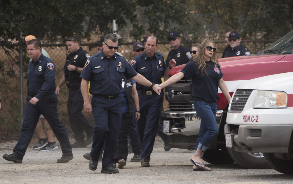 Firefighters gather as the procession for Redding fire inspector Jeremy Stoke passes in Redding, Calif., Thursday, Aug. 2, 2018. Stoke, who died last week in the Carr Fire, was being taken from the coroner's office to a funeral home. Fire officials say a massive blaze in Northern California that has killed six people and torched more than 1,000 homes grew overnight, fueled by wind. The California Department of Forestry and Fire Protection said Thursday firefighters made some gains and the blaze is now a third contained. (AP Photo/Michael Burke)