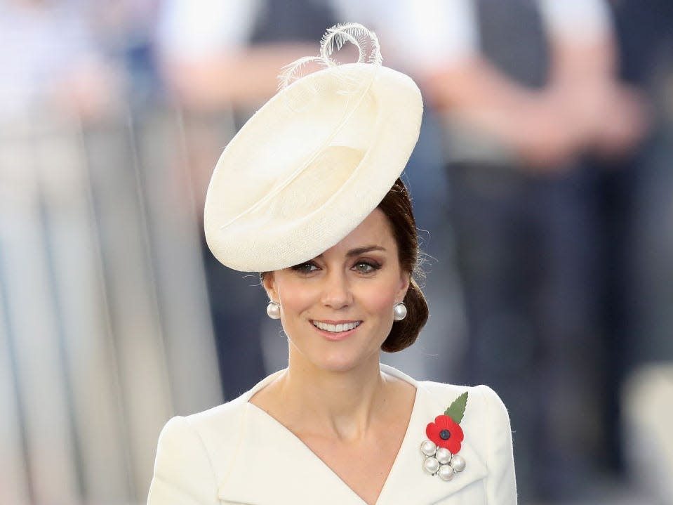 Kate Middleton wearing a white fascinator with a white dress.