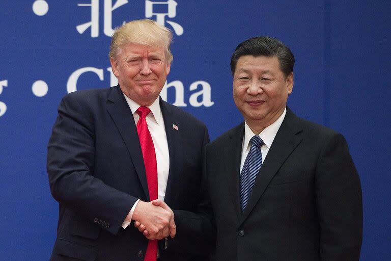 Esta foto de archivo tomada el 9 de noviembre de 2017 muestra al presidente de Estados Unidos, Donald Trump, Y al presidente de China, Xi Jinping, dándose la mano durante un evento de líderes empresariales en el Gran Salón del Pueblo en Pekín