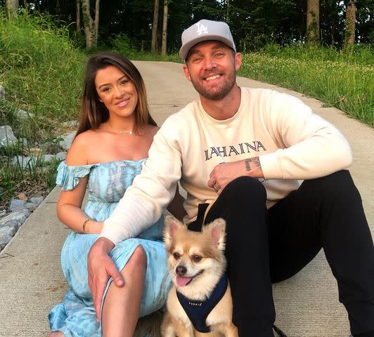 Taylor Mills Instagram Brett Young sitting with Taylor Mills Young and a dog outdoors.