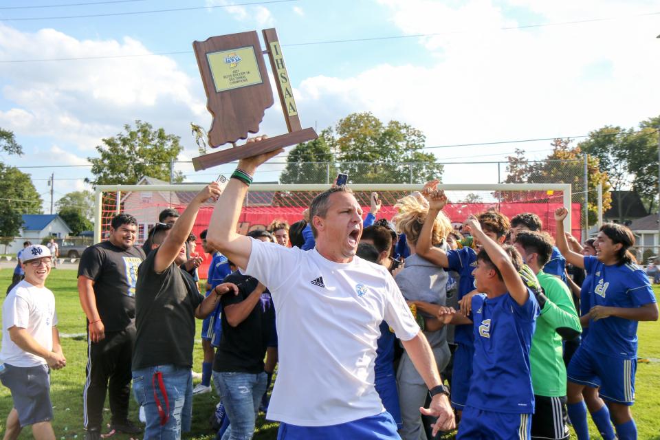 Elkhart head coach Todd Sheely celebrates with the trophy following last year's Sectional Final game against Penn at Goshen.