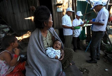 A woman carries her grandson as health officials collect mosquitos and larva at her home to check for Zika virus at a village in Phnom Penh, Cambodia February 4, 2016. REUTERS/Samrang Pring