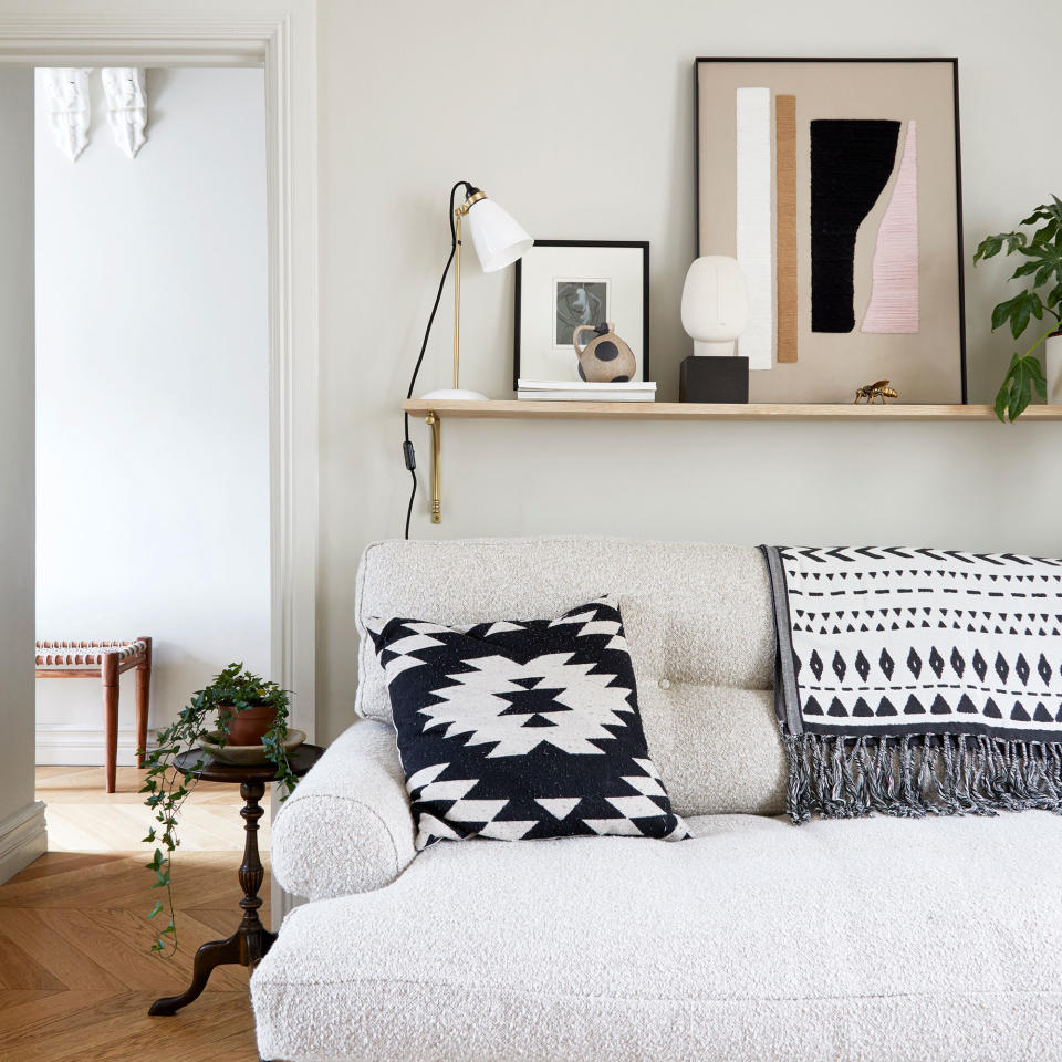 neutral living room with boucle sofa, low shelf and monochrome patterned cushion and throw