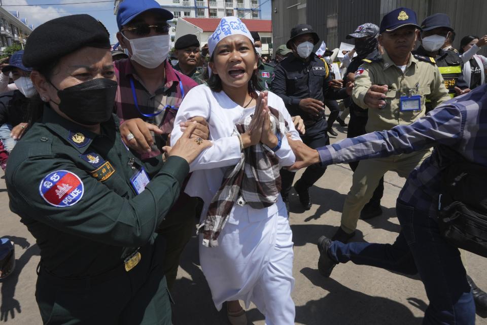 An environmental activist, center, is escorted by polices personnel near Phnom Penh Municipality Court, in Phnom Penh, Cambodia, Tuesday, July 2, 2024. Ten members of a nonviolent environmental activist group in Cambodia were convicted on Tuesday on charges of conspiracy to commit a crime, receiving prison sentences of six years each. (AP Photo/Heng Sinith)