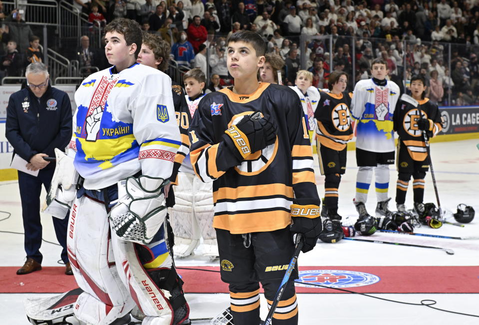 Ukraine and Boston Junior Bruins peewee teams stand together during the national anthems before a hockey game, Saturday, Feb, 11, 2023, in Quebec City. (Jacques Boissinot/The Canadian Press via AP)