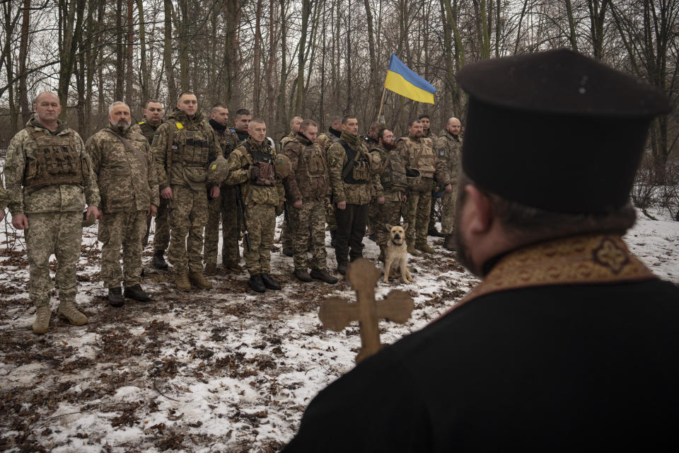A priest blesses Ukrainian servicemen of the Prince Roman the Great 14th Separate Mechanized Brigade as they stand in formation during a flag ceremony where some of them were honored for their bravery and accomplishments in battle, in the Kharkiv area, Ukraine, Saturday, Feb. 25, 2023. (AP Photo/Vadim Ghirda)