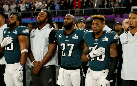 Players with the Philadelphia Eagles stand for the national anthem - Credit: Reuters