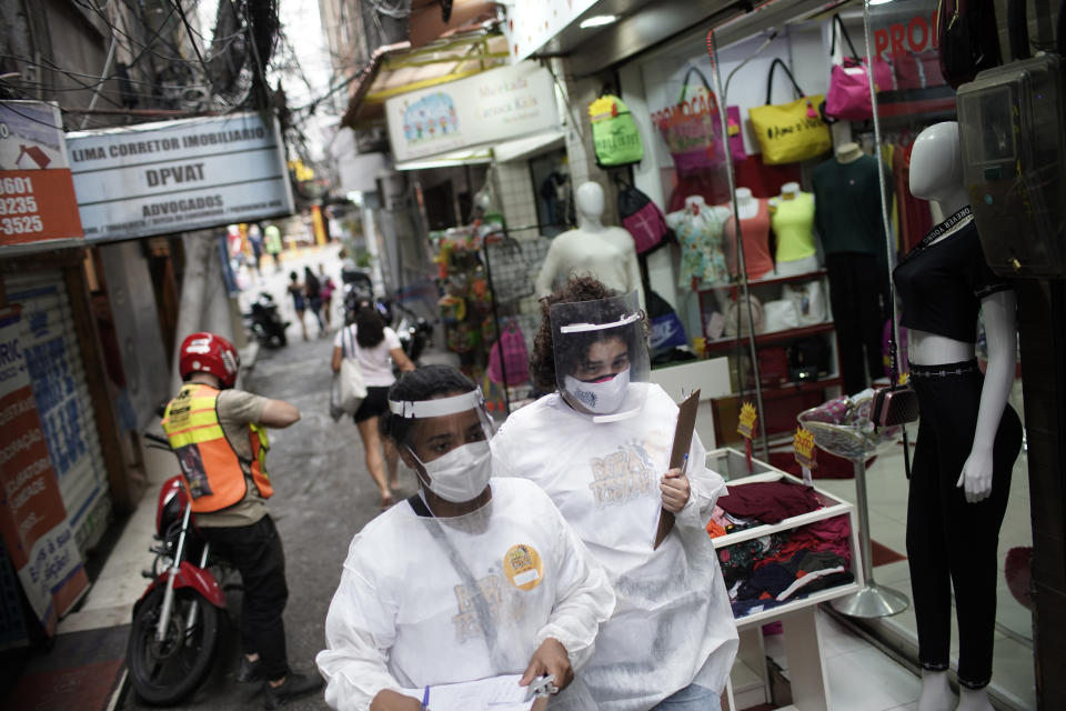 Health workers walk through the Rocinha slum to test people for COVID-19 as part of a rapid test campaign by the civilian organization "Bora Testar," or "Let's Test" in Rio de Janeiro, Brazil, Thursday, Oct. 8, 2020. Financed by crowdfunding and donations, the organization says it aims to test up to 300 people in the slum. (AP Photo/Silvia Izquierdo)