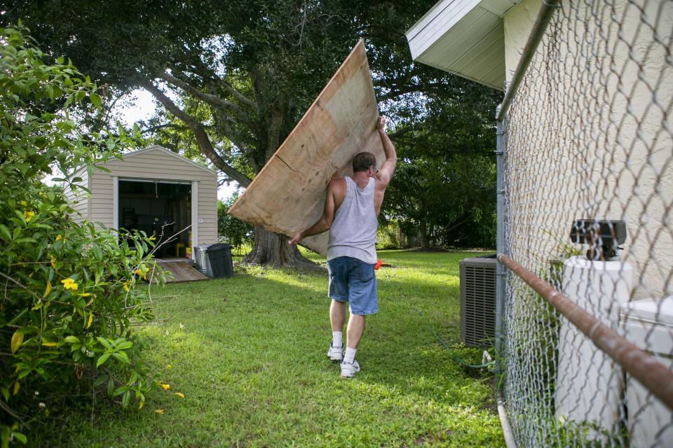 Colin Johnson carries plywood as he prepares to board a window at his father&#39;s home in preparation for Hurricane Dorian, Friday, Aug. 30, 2019, in Vero Beach, Fla. Johnson&#39;s father, Larry, unexpectedly died Thursday. (Matias J. Ocner/Miami Herald via AP)