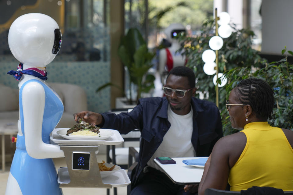 Robotic waiter Claire, delivers an order to customers at the Robot Cafe in Nairobi, Kenya Thursday, Aug. 29, 2024. The three robots, christened Claire, R24 and Nadia, are not programmed to have a full conversation with customers, but they can say "Your order is ready, Welcome" then people have to press an exit button after picking up their food from the tray. (AP Photo/Brian Inganga)