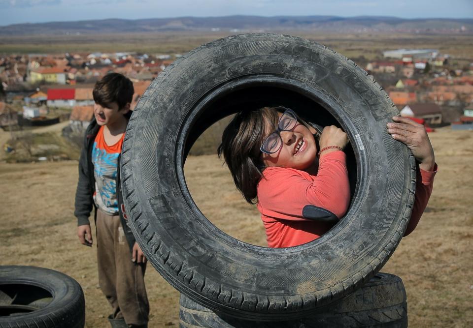 In this photo taken on Sunday, March 10, 2019, a little girl struggles to lift a tire during a ritual marking the upcoming Clean Monday, the beginning of the Great Lent, 40 days ahead of Orthodox Easter, on the hills surrounding the village of Poplaca, in central Romania's Transylvania region. Romanian villagers burn piles of used tires then spin them in the Transylvanian hills in a ritual they believe will ward off evil spirits as they begin a period of 40 days of abstention, when Orthodox Christians cut out meat, fish, eggs, and dairy. (AP Photo/Vadim Ghirda)