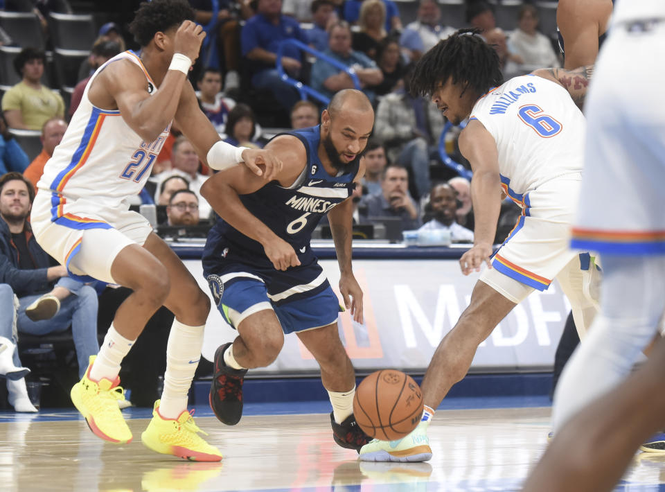 Minnesota Timberwolvesguard Jordan McLaughlin, center, tries to push past Oklahoma City Thunder forwards Aaron Wiggins, left, and Jaylin Williams, right, in the first half of an NBA basketball game, Sunday, Oct. 23, 2022, in Oklahoma City. (AP Photo/Kyle Phillips)