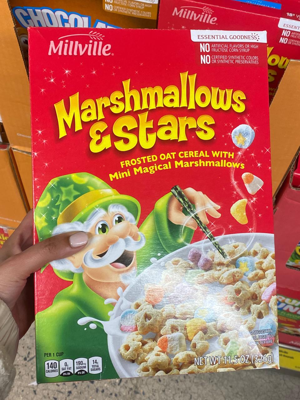 Hand holding red box of marshmallows and stars cereal at Aldi