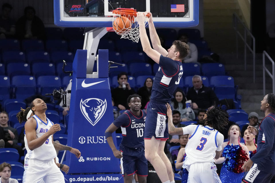 UConn center Donovan Clingan, center, dunks as DePaul center Churchill Abass, left, looks on during the second half of an NCAA college basketball game in Chicago, Wednesday, Feb. 14, 2024. UConn won 101-65. (AP Photo/Nam Y. Huh)