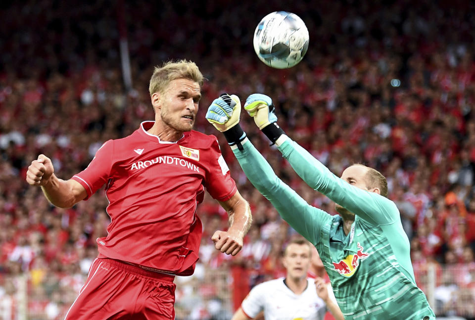 Berlin's Sebastian Andersson, left, vies for the ball with Leipzig goalkeeper Peter Gulacsi, during the German Bundesliga soccer match between Union Berlin and RB Leipzig, at the Stadion An der Alten Foersterei, in Berlin, Sunday, Aug. 18, 2019. (Britta Pedersen/dpa via AP)