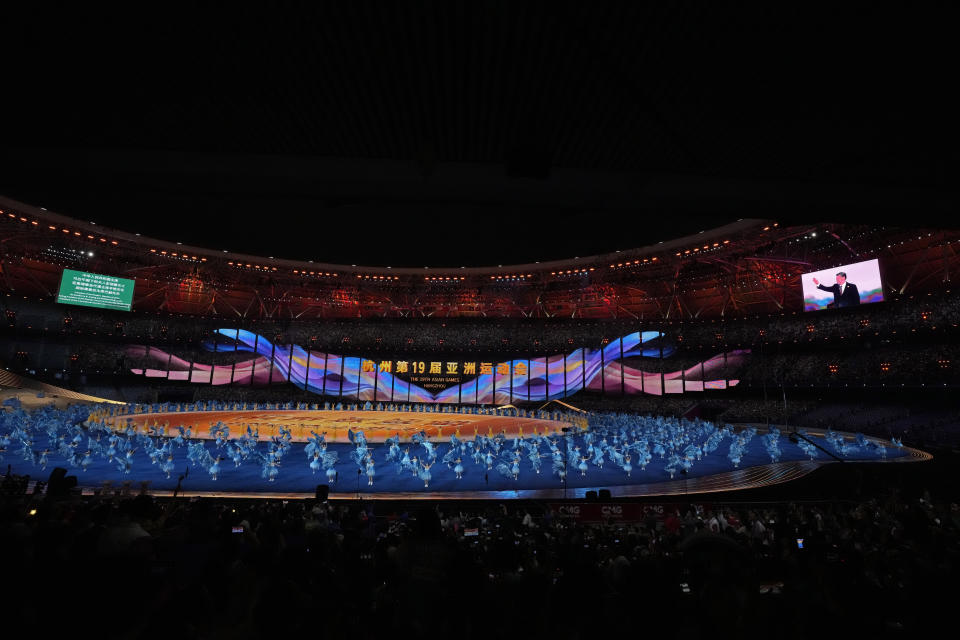 Artists perform as live pictures of Chinese President Xi Jinping waving the spectators are displayed on a large screen during the during the opening ceremony of the 19th Asian Games in Hangzhou, China, Saturday, Sept. 23, 2023. (AP Photo/Aijaz Rahi)