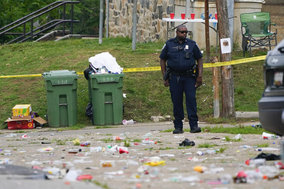 Un policía permanece de pie en el sitio donde hubo un tiroteo masivo el domingo 2 de julio de 2023, en el Distrito Sur de Baltimore. (AP Foto/Julio Cortez)
