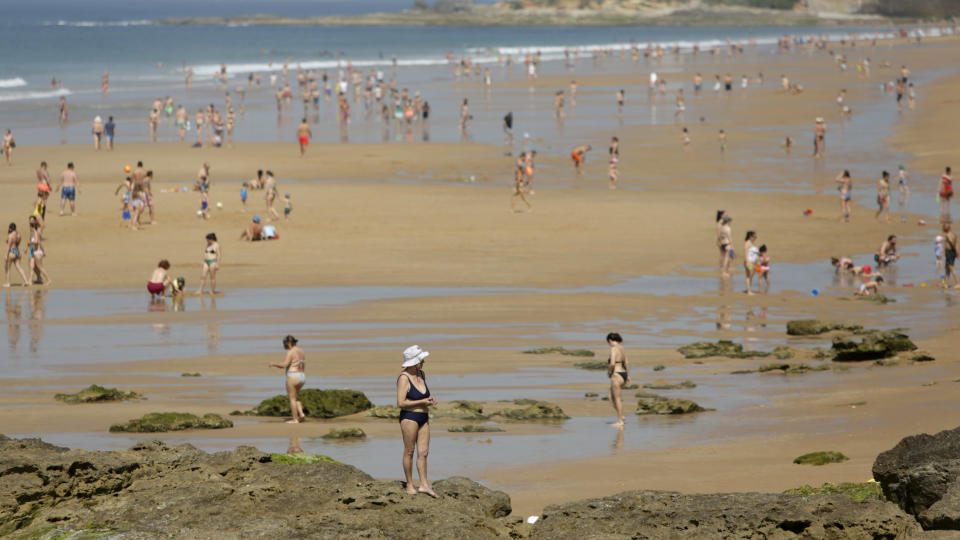 People walk along the water at the Carcavelos beach, outside Lisbon, Tuesday, May 26, 2020. As the government eases the coronavirus lockdown rules, people have been allowed back on the beaches with recommendations to keep social distance. Portugal is experience temperatures above average, reaching 30C in Lisbon. (AP Photo/Armando Franca)