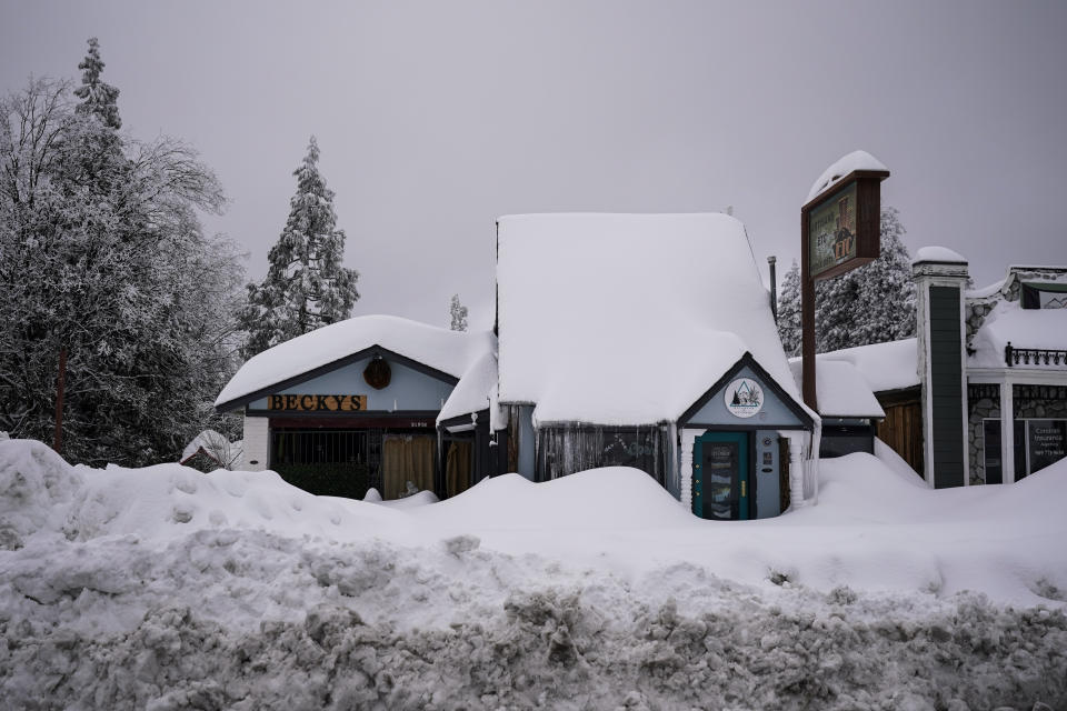 Snow is piled up on buildings in Running Springs, Calif., Tuesday, Feb. 28, 2023. Beleaguered Californians got hit again Tuesday as a new winter storm moved into the already drenched and snow-plastered state, with blizzard warnings blanketing the Sierra Nevada and forecasters warning residents that any travel was dangerous. (AP Photo/Jae C. Hong)